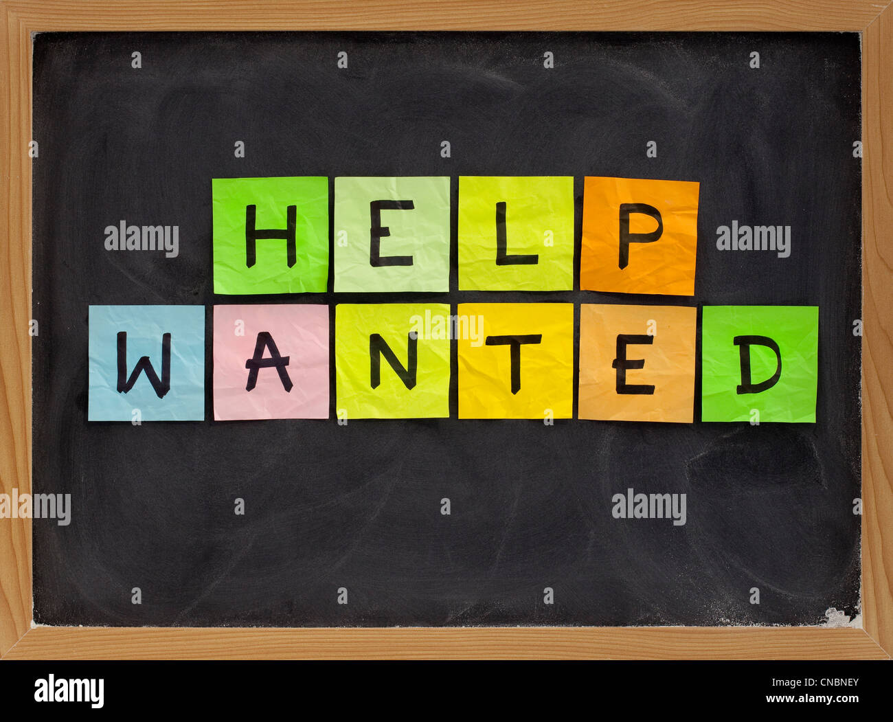 help wanted - colorful sticky notes sign on blackboard with white chalk texture Stock Photo