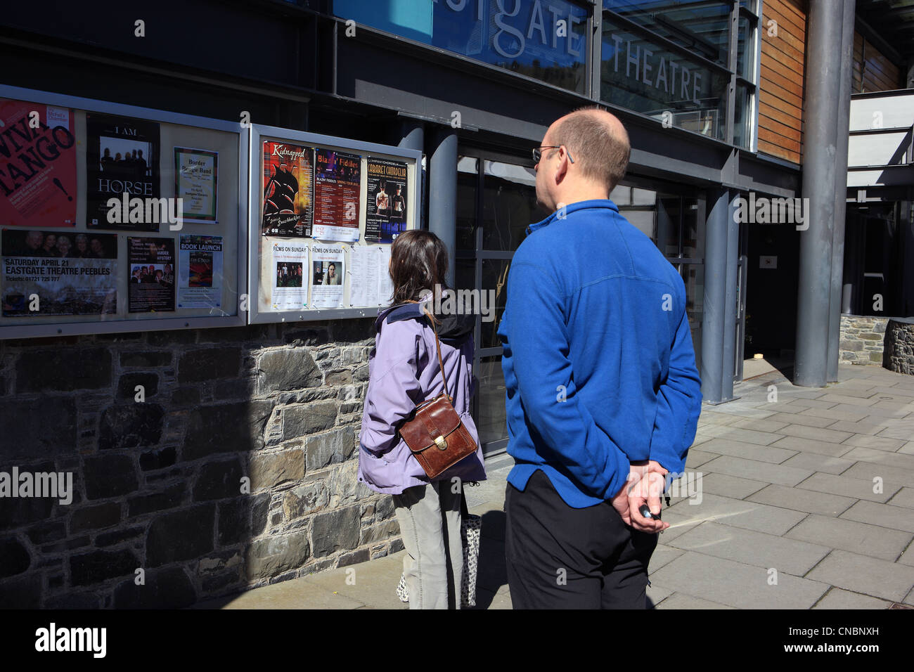 Man and woman looking at 'what's on' posters outside the Eastgate Theatre in Peebles Stock Photo