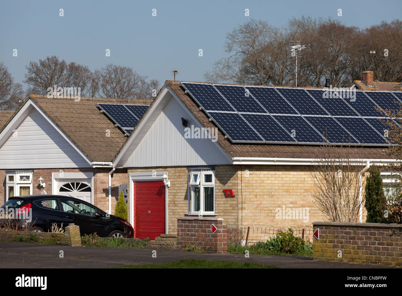 solar electric generation panels on the roofs of two urban bungalows Stock Photo