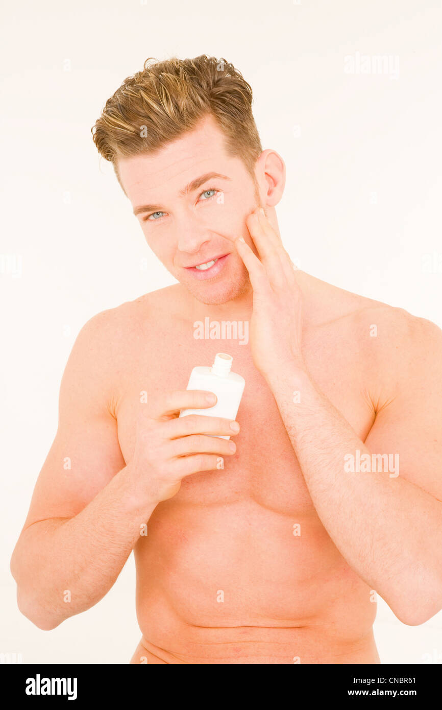 Young man applying aftershave Stock Photo