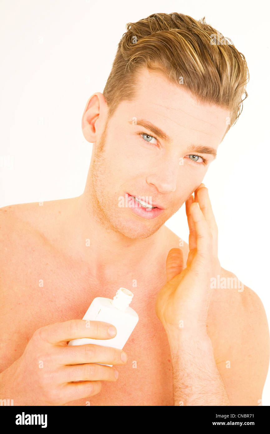 Young man applying aftershave Stock Photo