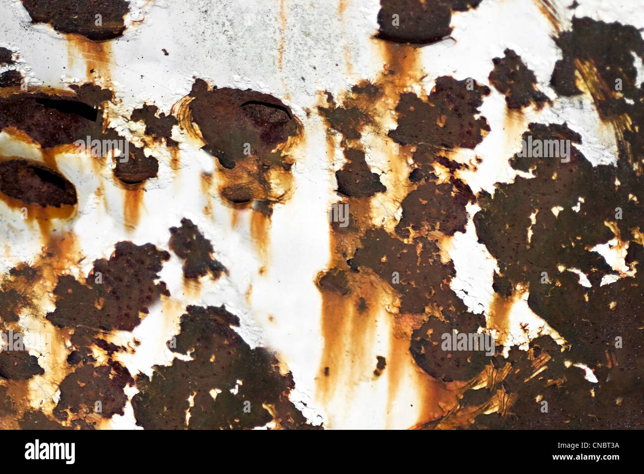 Closeup of rusted metal with chipped paint and holes. Stock Photo