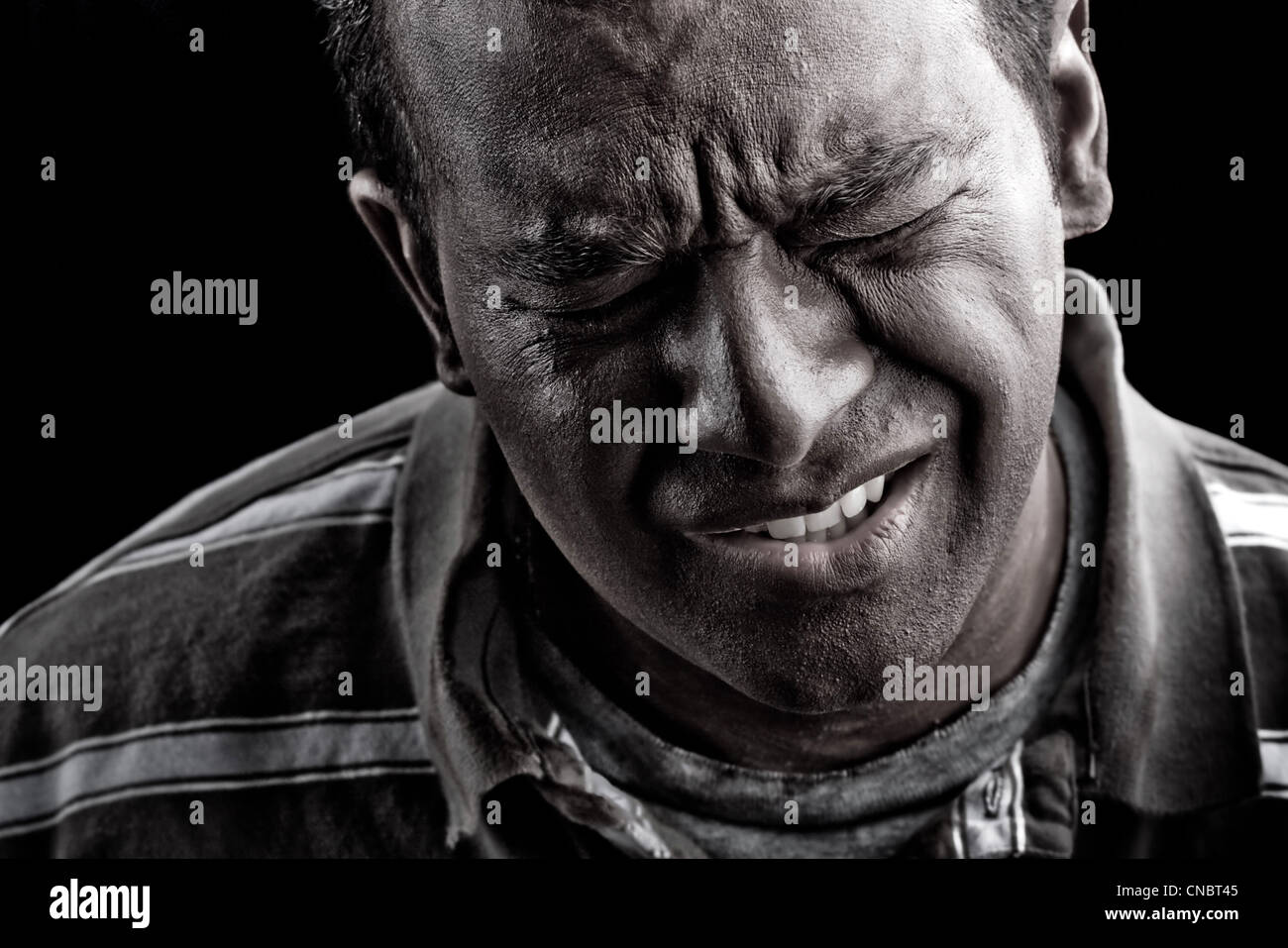 Low key portrait of a man suffering from extreme anguish pain or other  hardship over a black background Stock Photo - Alamy
