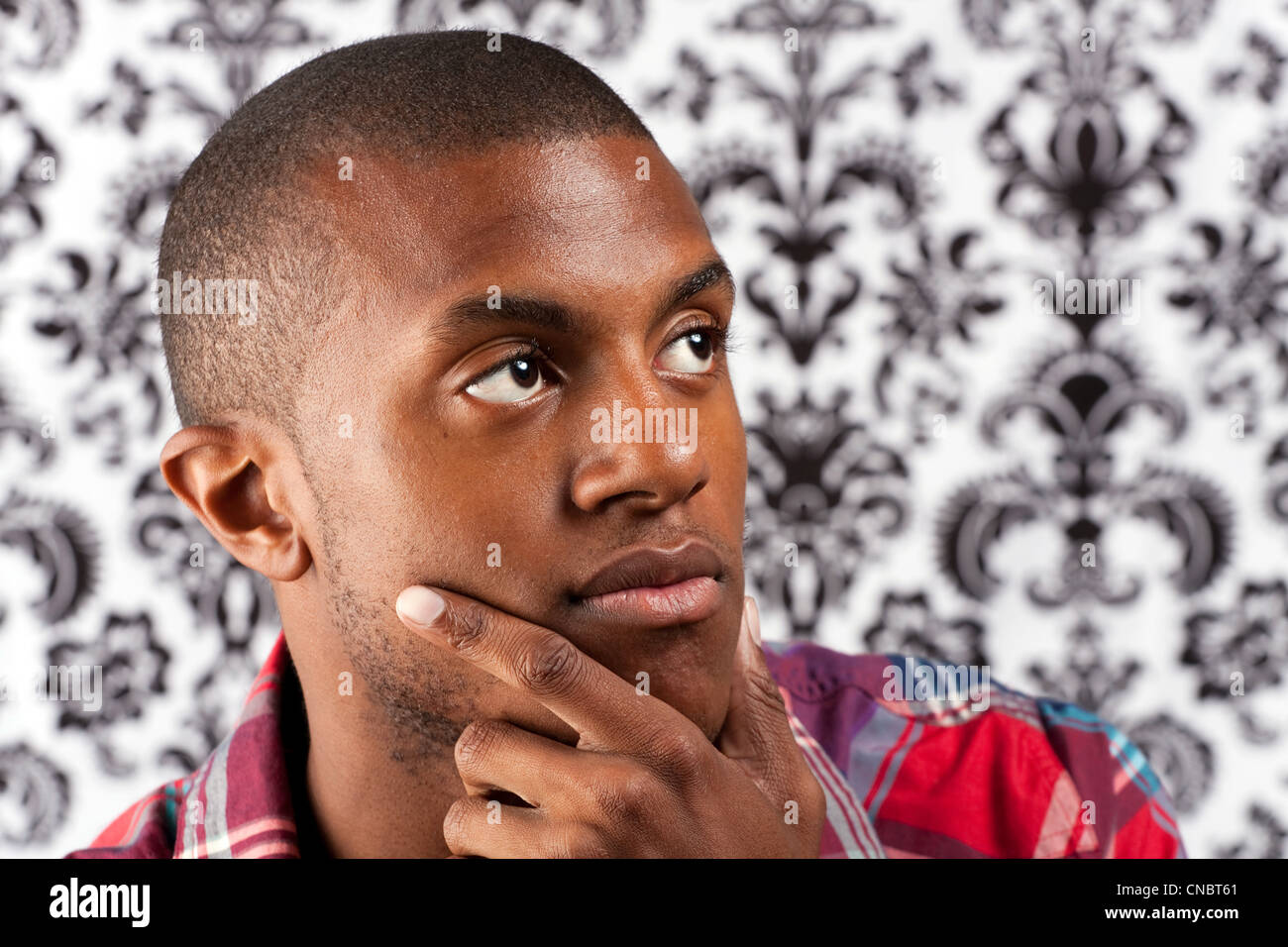 A young African American man in his twenties and his hand on his chin ...