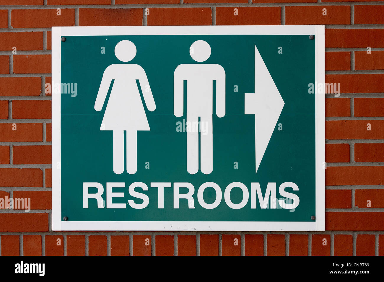 Restrooms sign on a red brick wall Stock Photo