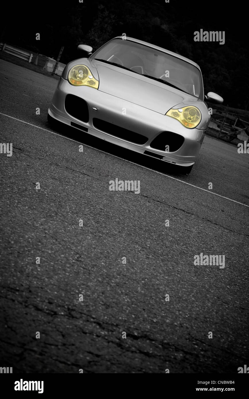 A silver sports car with the yellow headlights highlighted in selective color. Plenty of copyspace for your text. Stock Photo