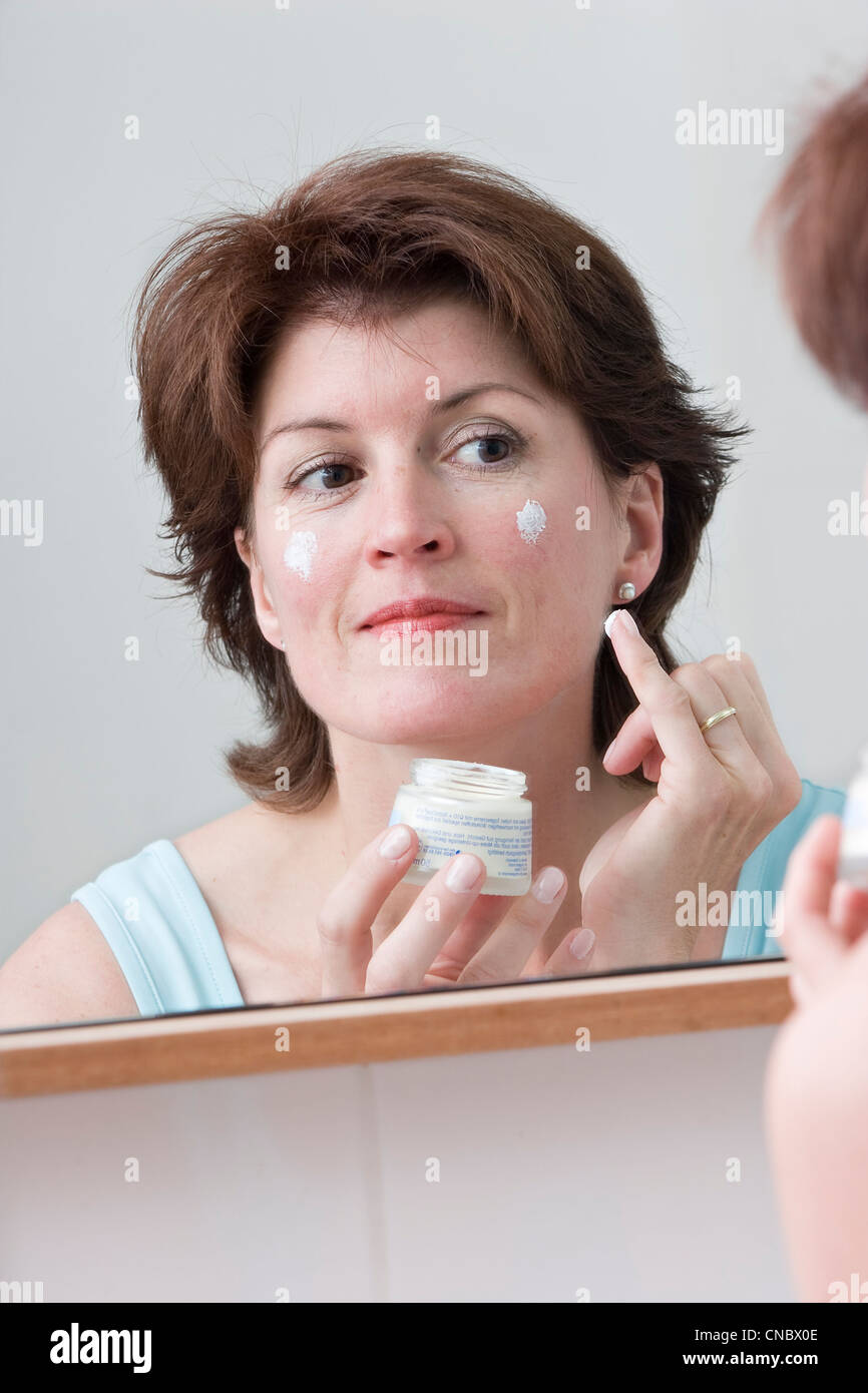 Woman putting skin lotion in mirror hires stock photography and images