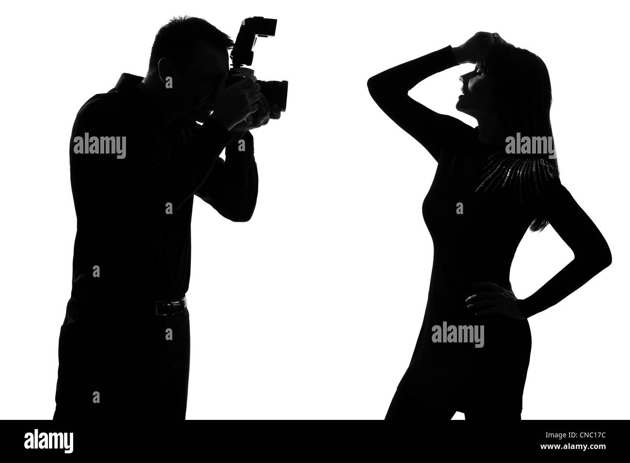 one caucasian  couple man photographer photographing and woman fashion model posing in studio silhouette isolated on white background Stock Photo