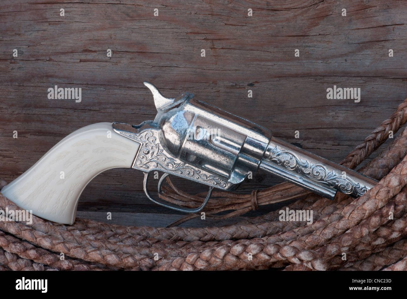 Gun toy replica on lariat rope with wood background and text space. Stock Photo