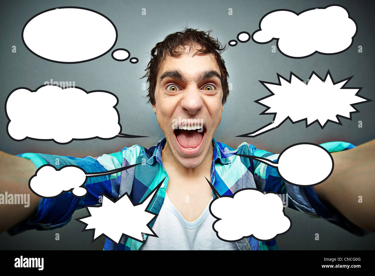 Young man shouting angrily or crazily at camera, numerous speech bubbles Stock Photo