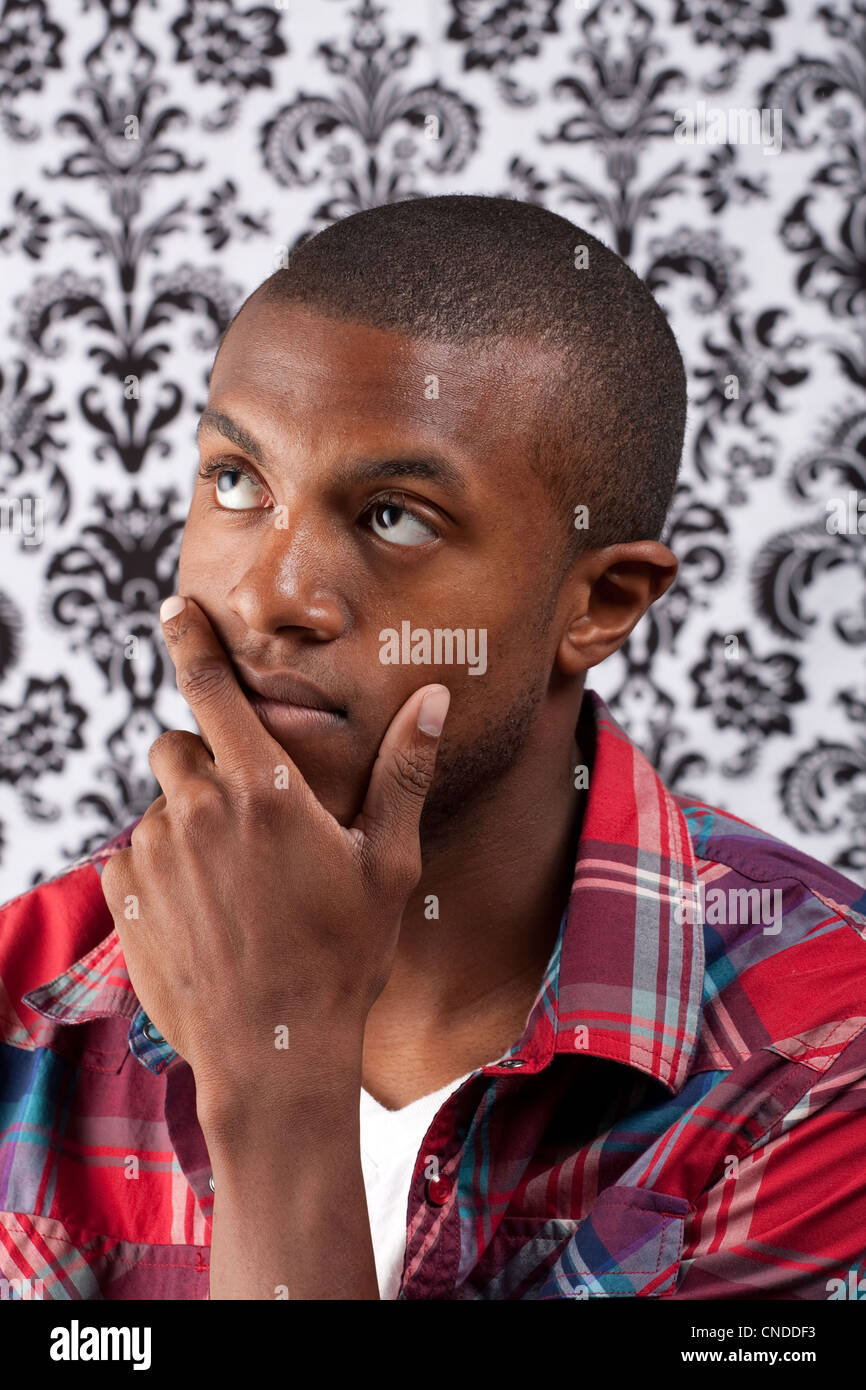 A young African American man in his twenties and his hand on his chin ...