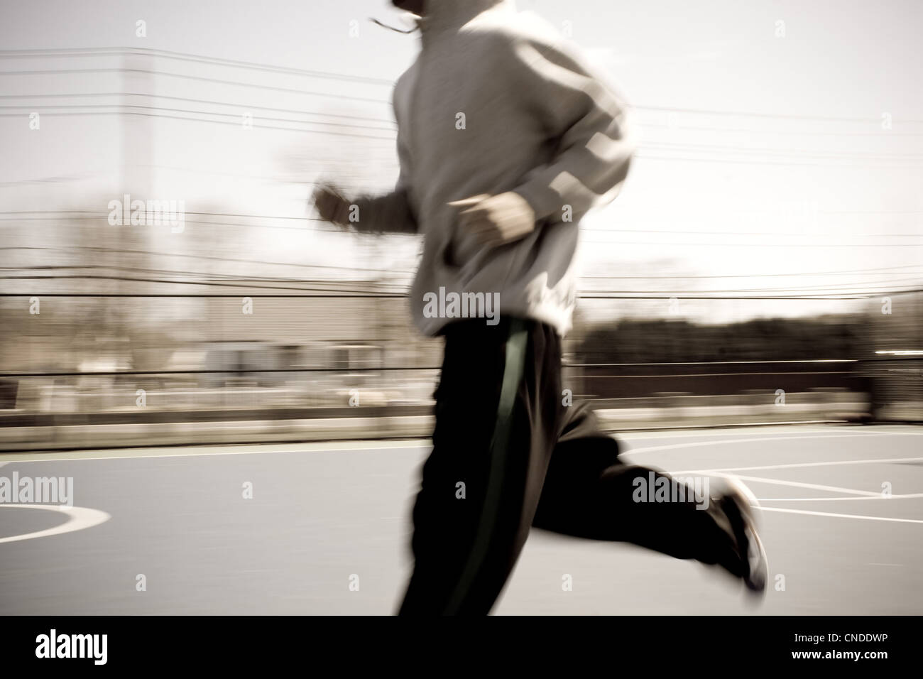 Abstract blur of a young man warming up by jogging at the basketball court. Intentional motion blur. Stock Photo
