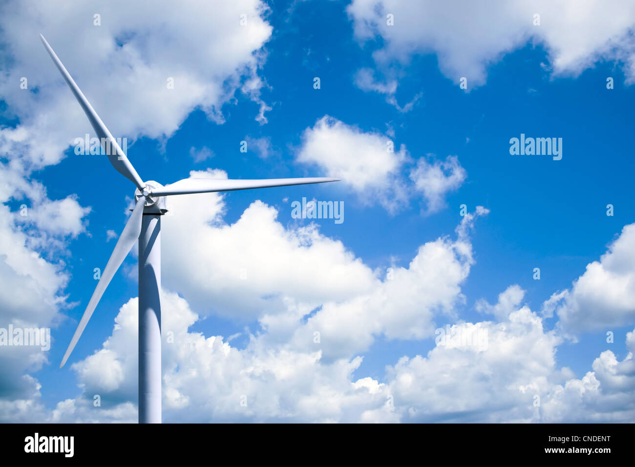 A single wind turbine over a cloud filled blue sky. Stock Photo