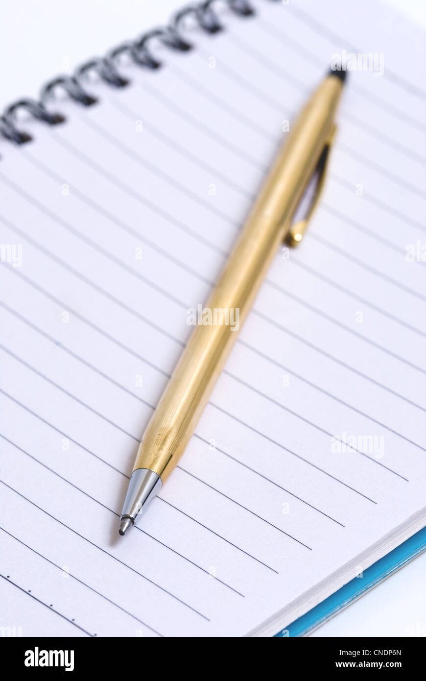 Macro image of a gold pen on lined paper notebook, business concept. Stock Photo
