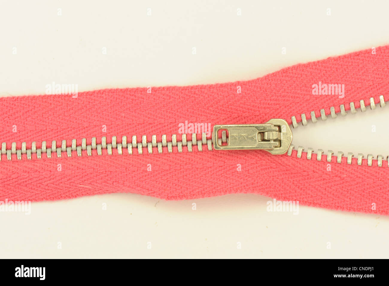 zip zipper red showing toggle taken on a white background sewing dressmaking Stock Photo