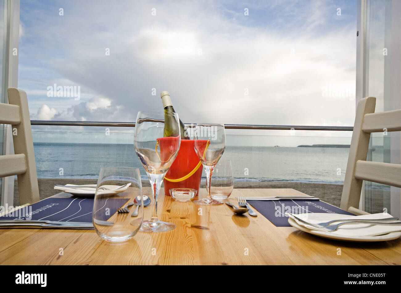 Restaurant table set out with white wine over looking the sea Stock Photo