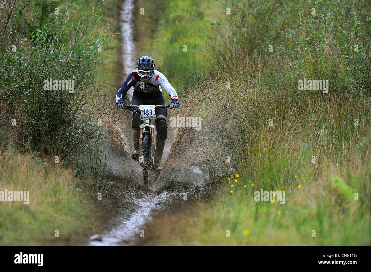 A mountain biker splashes through a muddy puddle whilst racing in South
