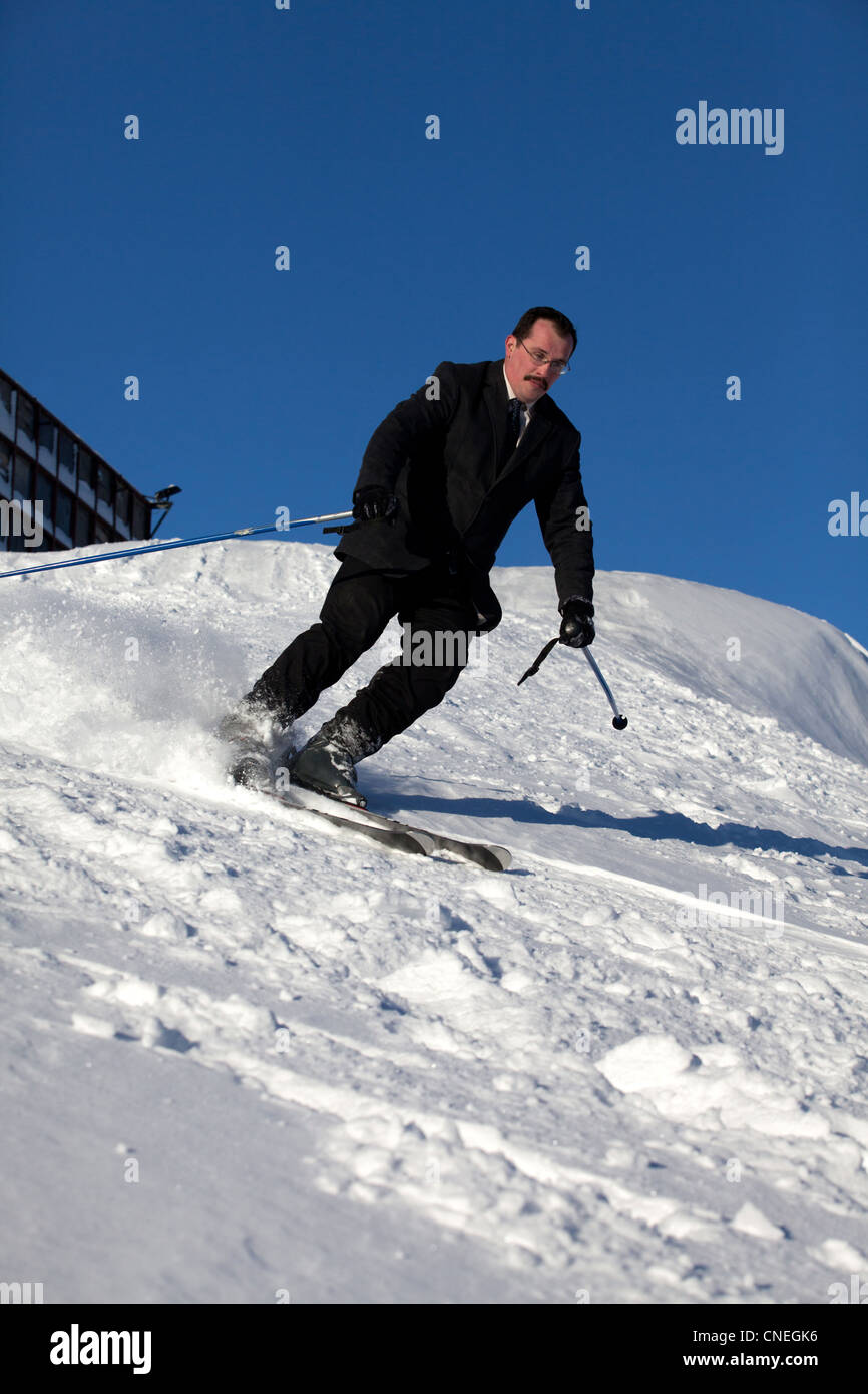 Man in business sute on ski going down Stock Photo