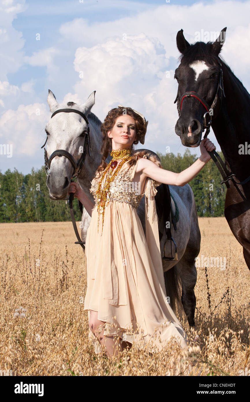 The woman in a beautiful old style dress with horse has a rest before ...