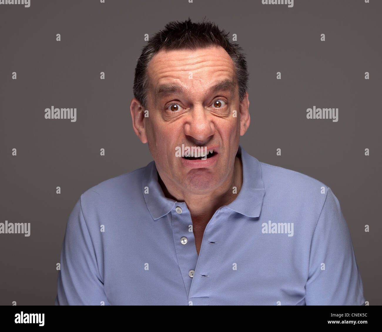 Middle Age Man Pulling Funny Grimace Face on Grey Background Stock Photo