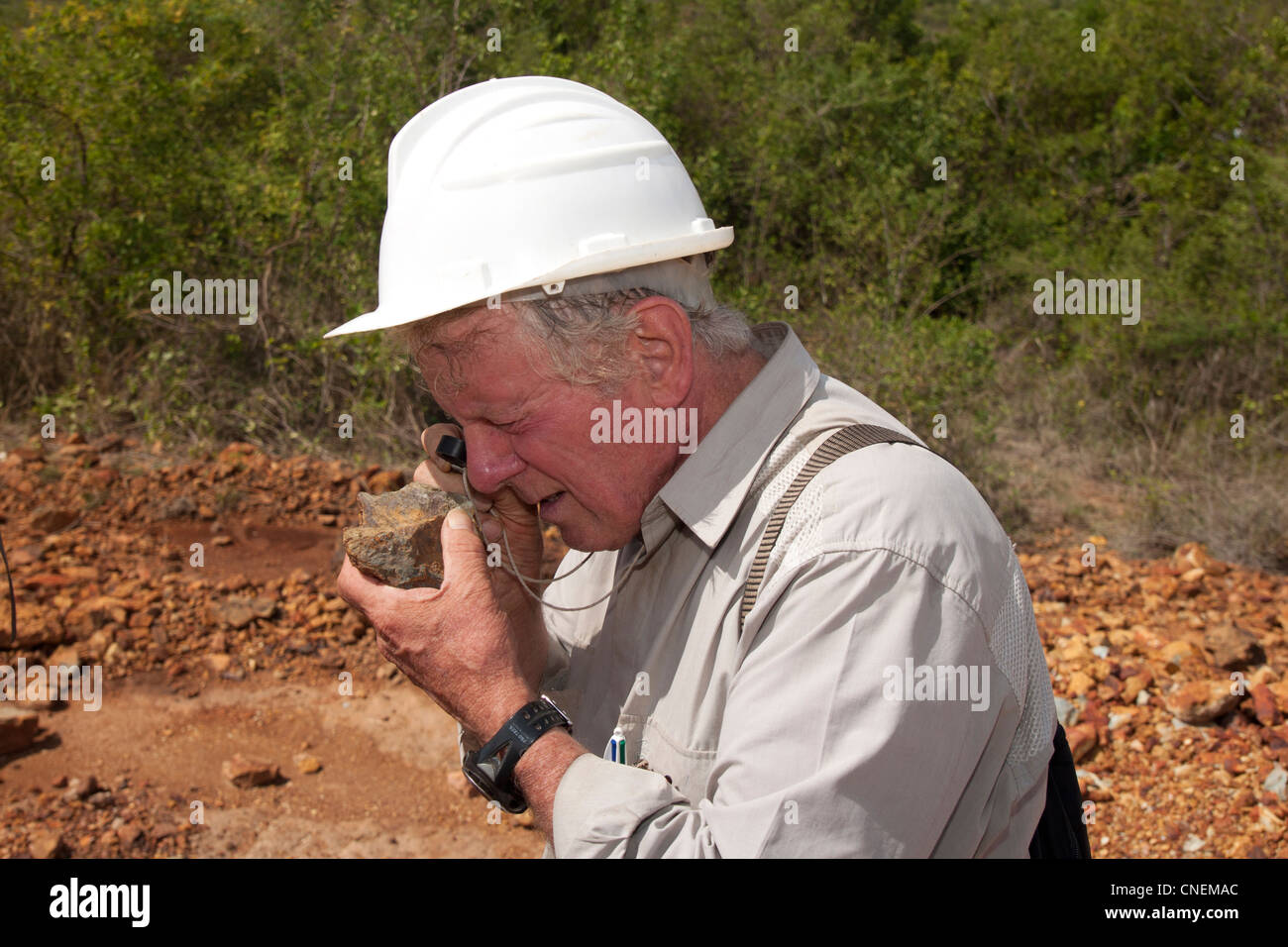 Senior exploration geologist analysing rock samples with a hand lens at