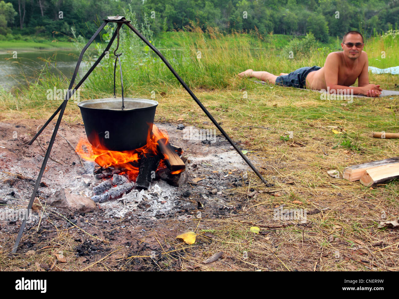 camping - kettle over campfire and lying tourist Stock Photo - Alamy
