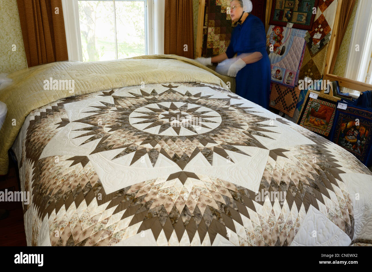 Mennonite seamstress in a bedroom showing handmade quilts near St
