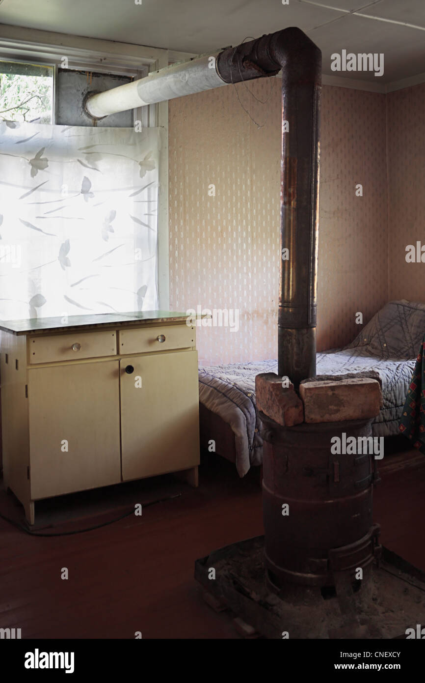 The interior of a poor rural room with a stove and chimney inside Stock Photo