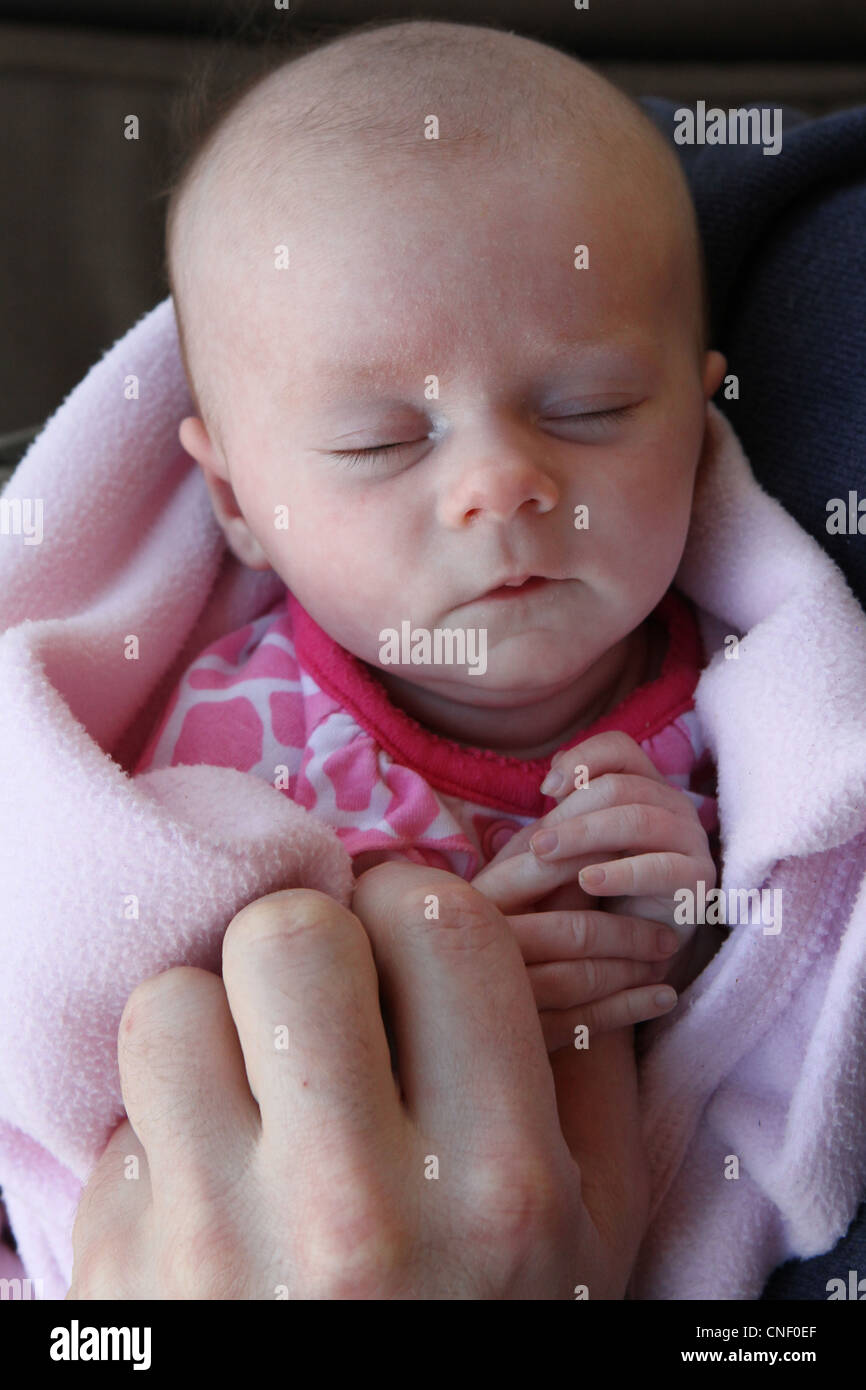 A sleeping newborn being held by her father Stock Photo Alamy