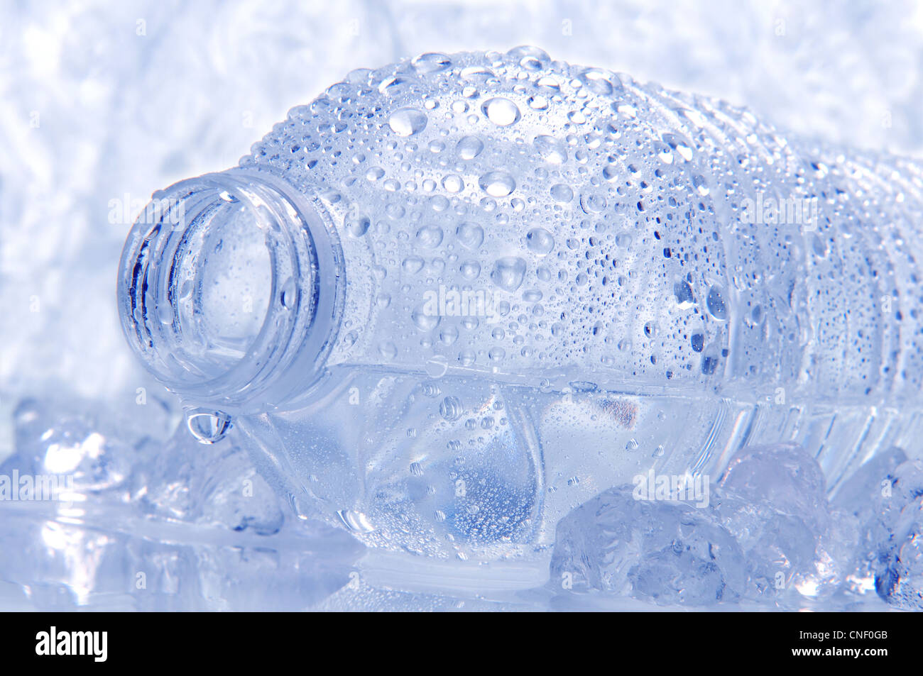 Closeup of a water bottle laying on its side with droplets and drip coming out of the opening. Stock Photo
