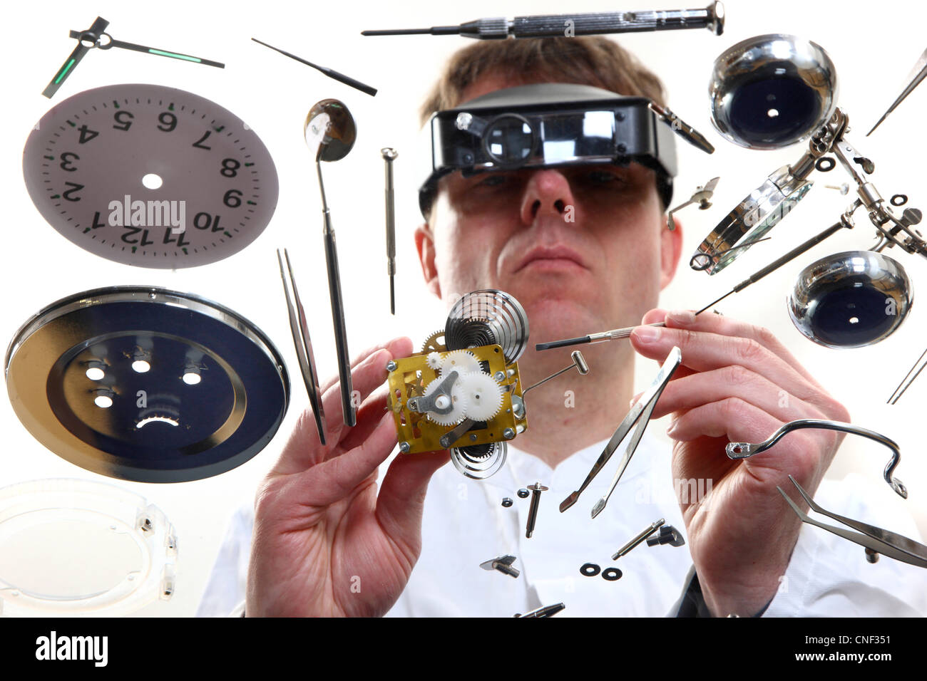 Precision mechanics, watchmakers, in repairing a watch, alarm clock, with magnifying glasses. Stock Photo