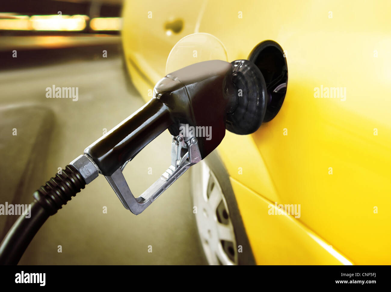 yellow car at gas station being filled with fuel Stock Photo Alamy