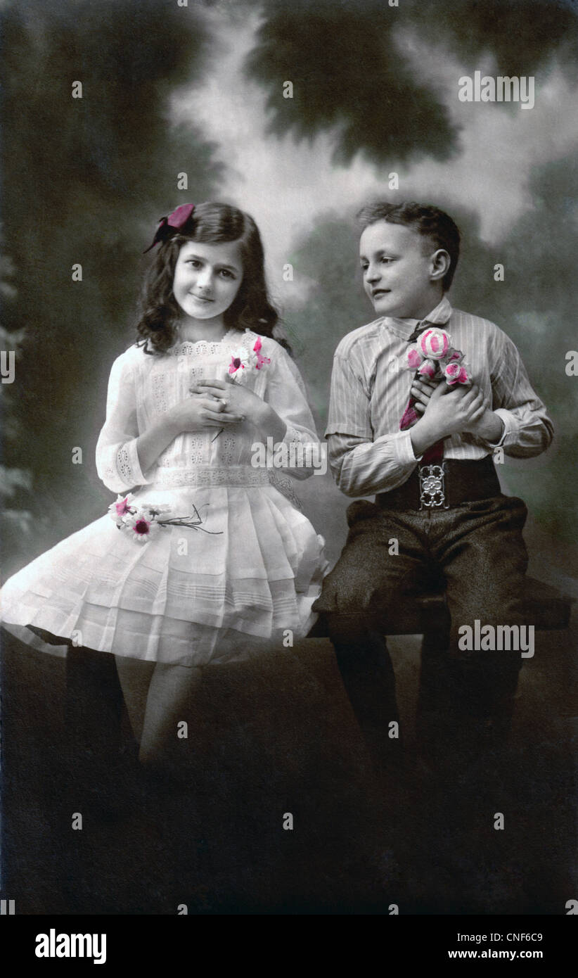 Vintage photograph of a young boy and girl with flowers during a romantic moment, circa 1916. Stock Photo