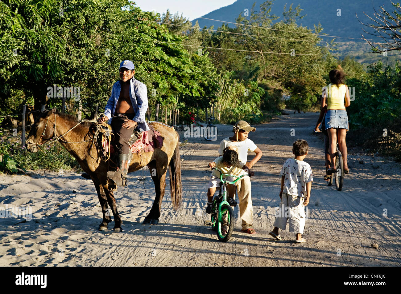Nicaragua Isla Ometepe Lake Nicaragua happy cowboy family riding horse and bike together after getting cattle back to the farm Stock Photo