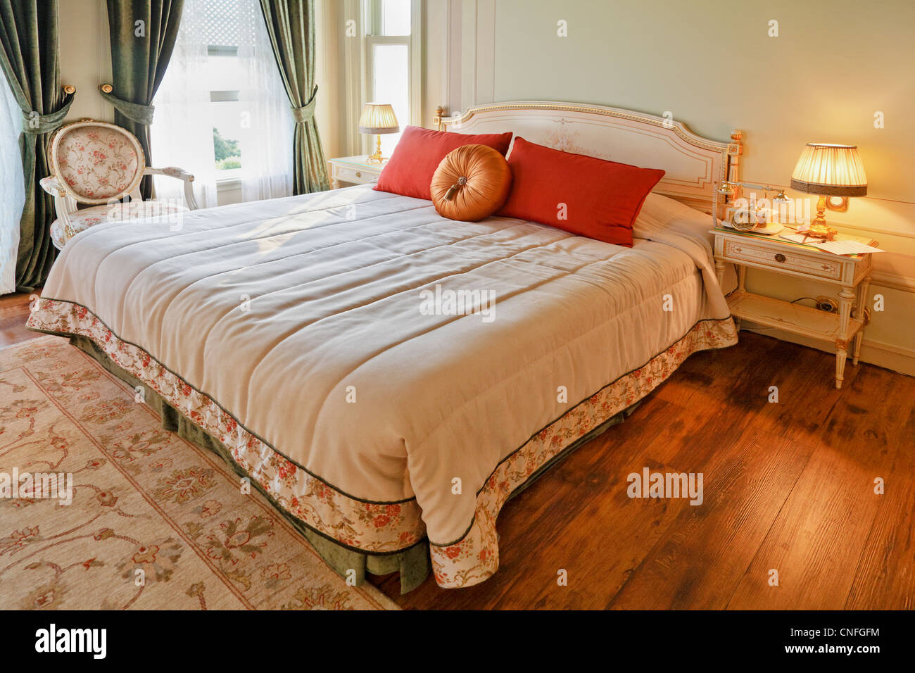 Horizontal shot of luxurious bedroom, fine appointed detail with white bedrobes and ornate bedside table Stock Photo