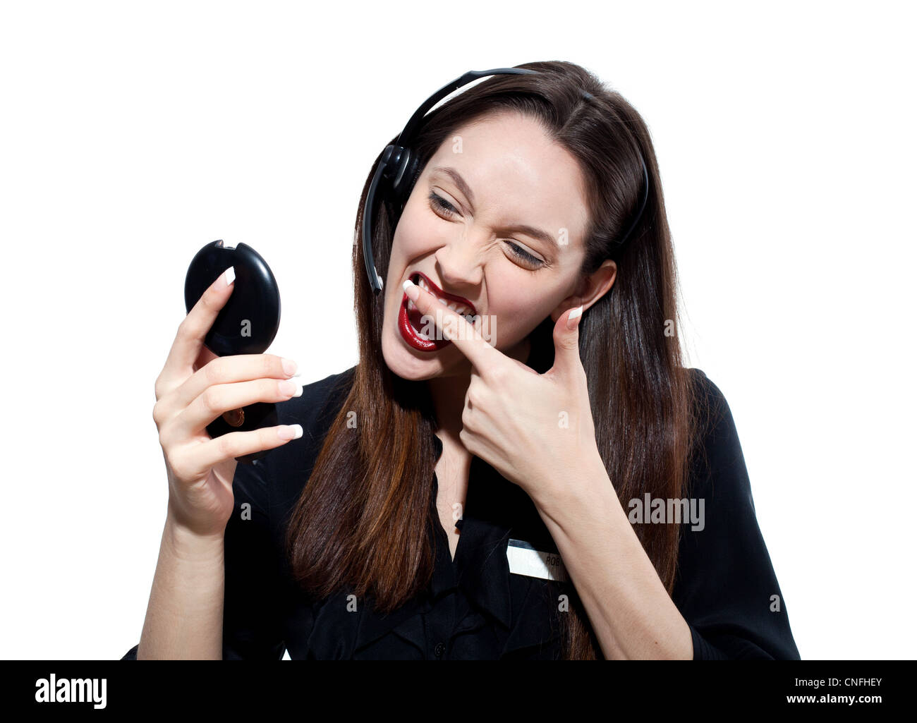 Woman with headset, wiping lipstick off her teeth Stock Photo