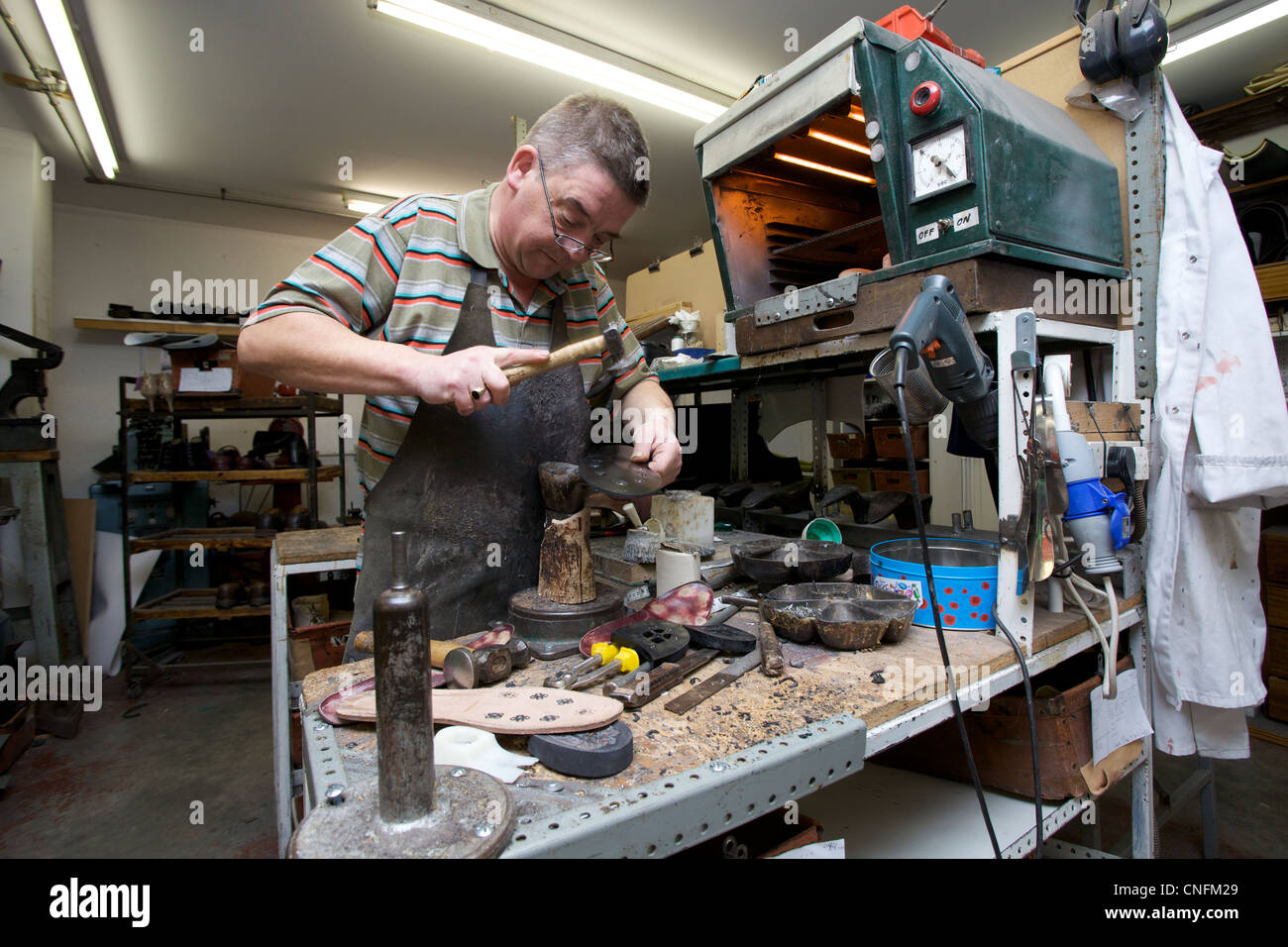 Cobbler working on the making of a shoe. Stock Photo
