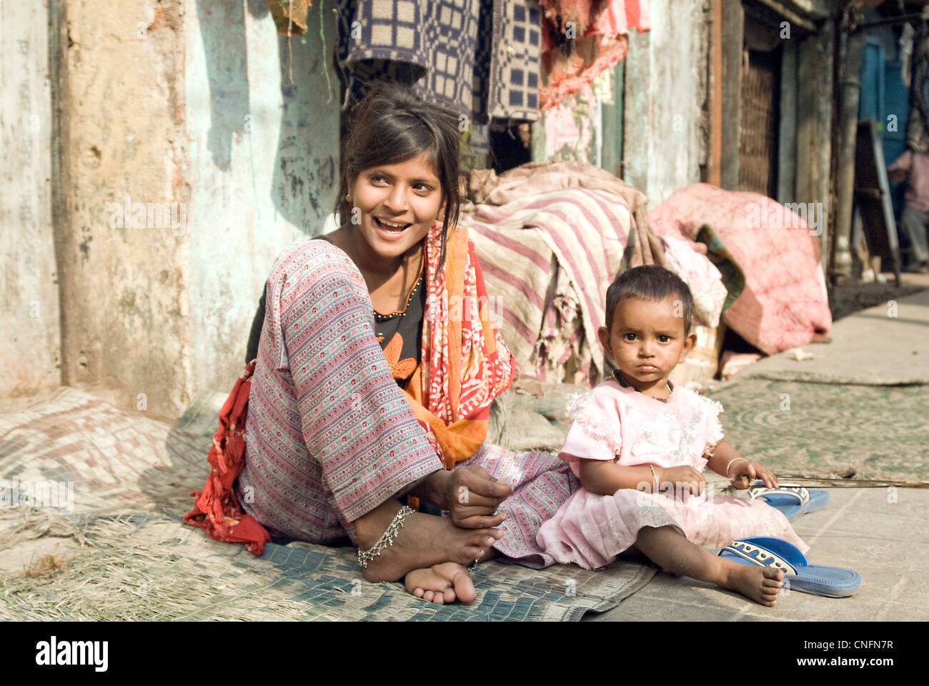 Girl with kid sitting in front of their house in Kolkata slum area Stock Photo