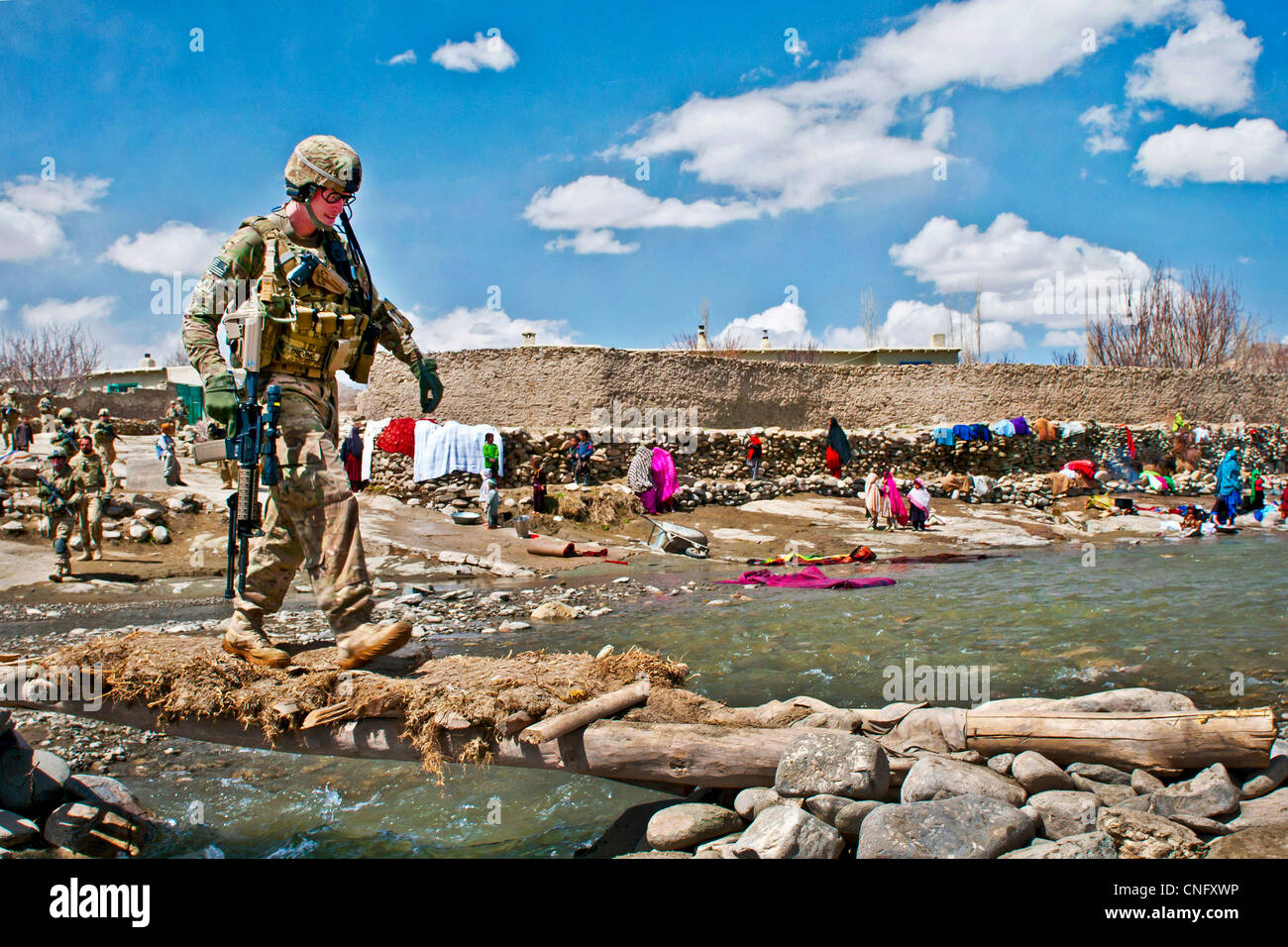 A US soldier walks across a primitive foot bridge over a swollen river on patrol April 4, 2012 outside of the village of Marzak, Afghanistan. Marzak has historically been a stronghold for the insurgency over the past decade until the Afghan and US forces established a local police force and secured Stock Photo