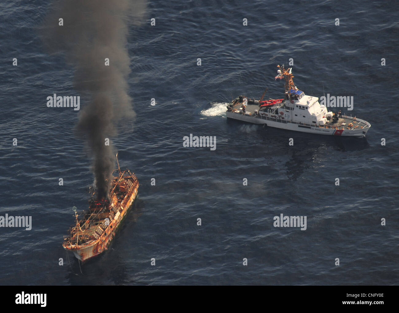 The Japanese fishing vessel Ryou-Un Maru burns after the US Coast Guard Cutter Anacapa (right) fired on it with explosive ammunition April 5, 2012 in the Gulf of Alaska. The trawler known as the ghost ship has been floating across the Pacific after being cast to sea by the magnitude 9.0 earthquake a Stock Photo