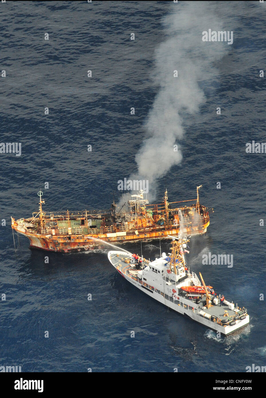 The Japanese fishing vessel Ryou-Un Maru burns after the US Coast Guard Cutter Anacapa (right) fired on it with explosive ammunition April 5, 2012 in the Gulf of Alaska. The trawler known as the ghost ship has been floating across the Pacific after being cast to sea by the magnitude 9.0 earthquake a Stock Photo