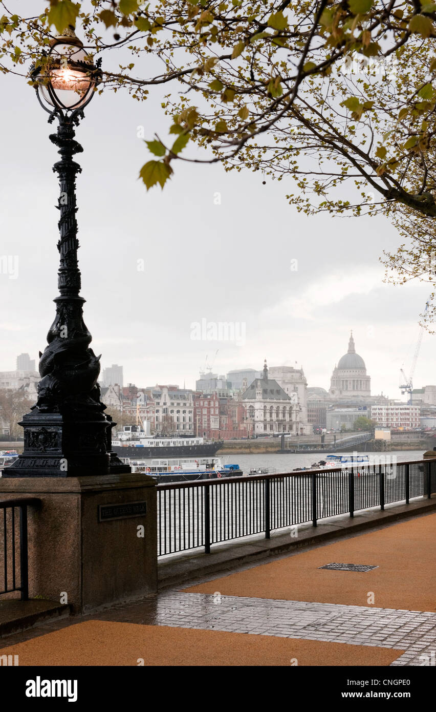 Queens Walk, South Bank, London  looking towards St Paul's Cathedral after a Spring shower with lit Victorian light Stock Photo