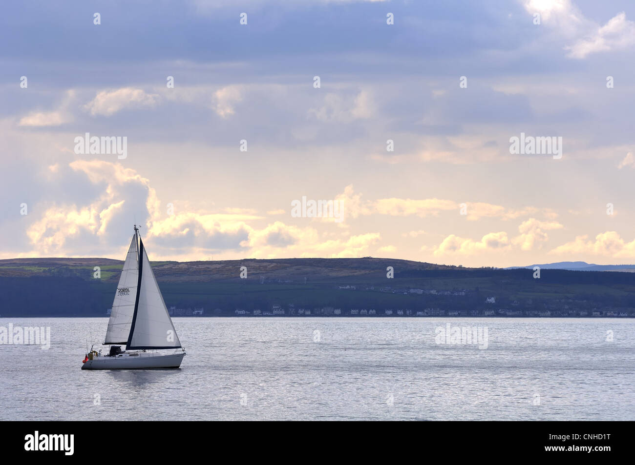 A small yacht comes to the end of it's journey as the sun sets on the River Clyde estuary near Largs, Ayrshire, Scotland, UK. Stock Photo