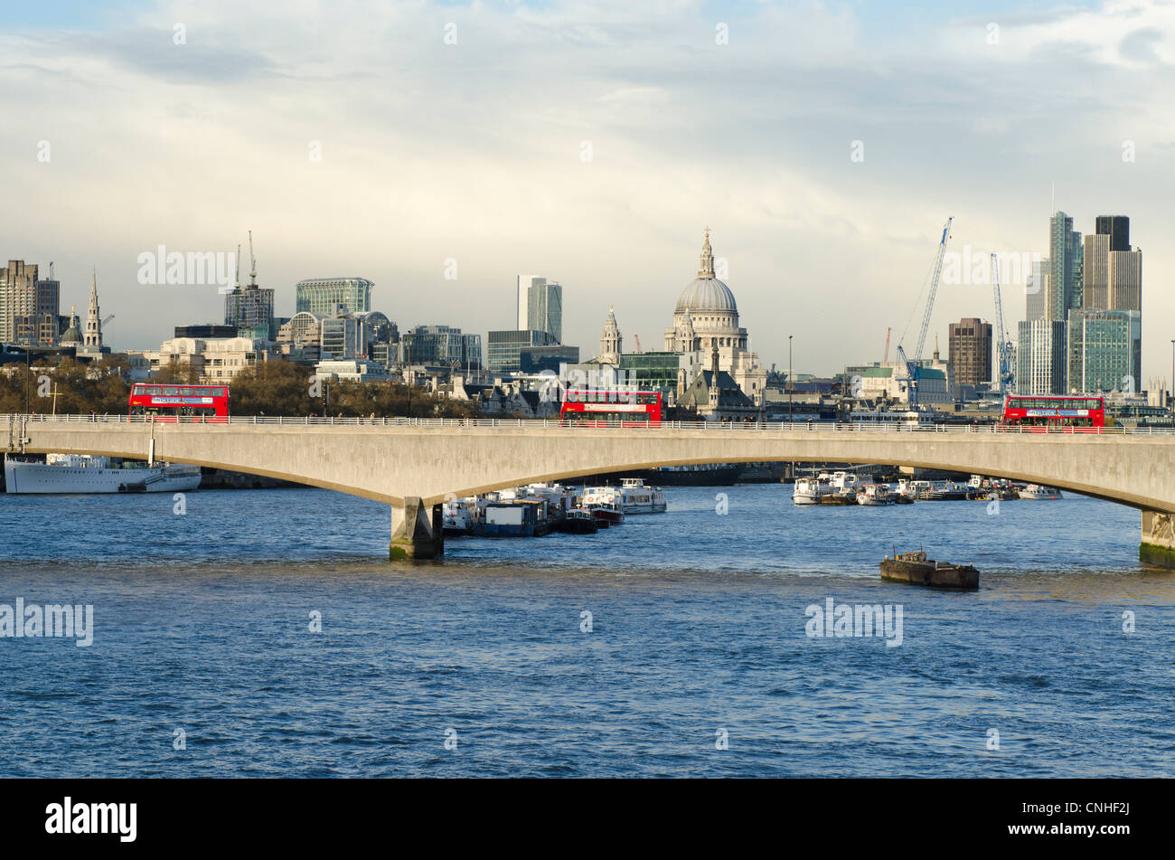 Three red buses on Waterloo Bridge London Skyline across river Thames London Uk. St Pauls Stock Photo