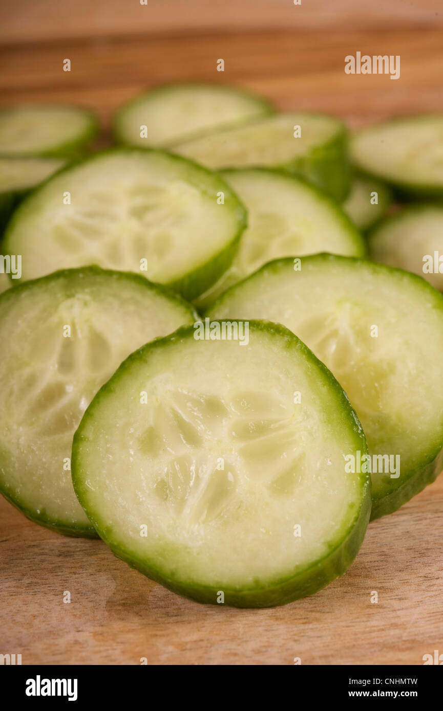 Sliced continental cucumber on a wooden chopping board Stock Photo