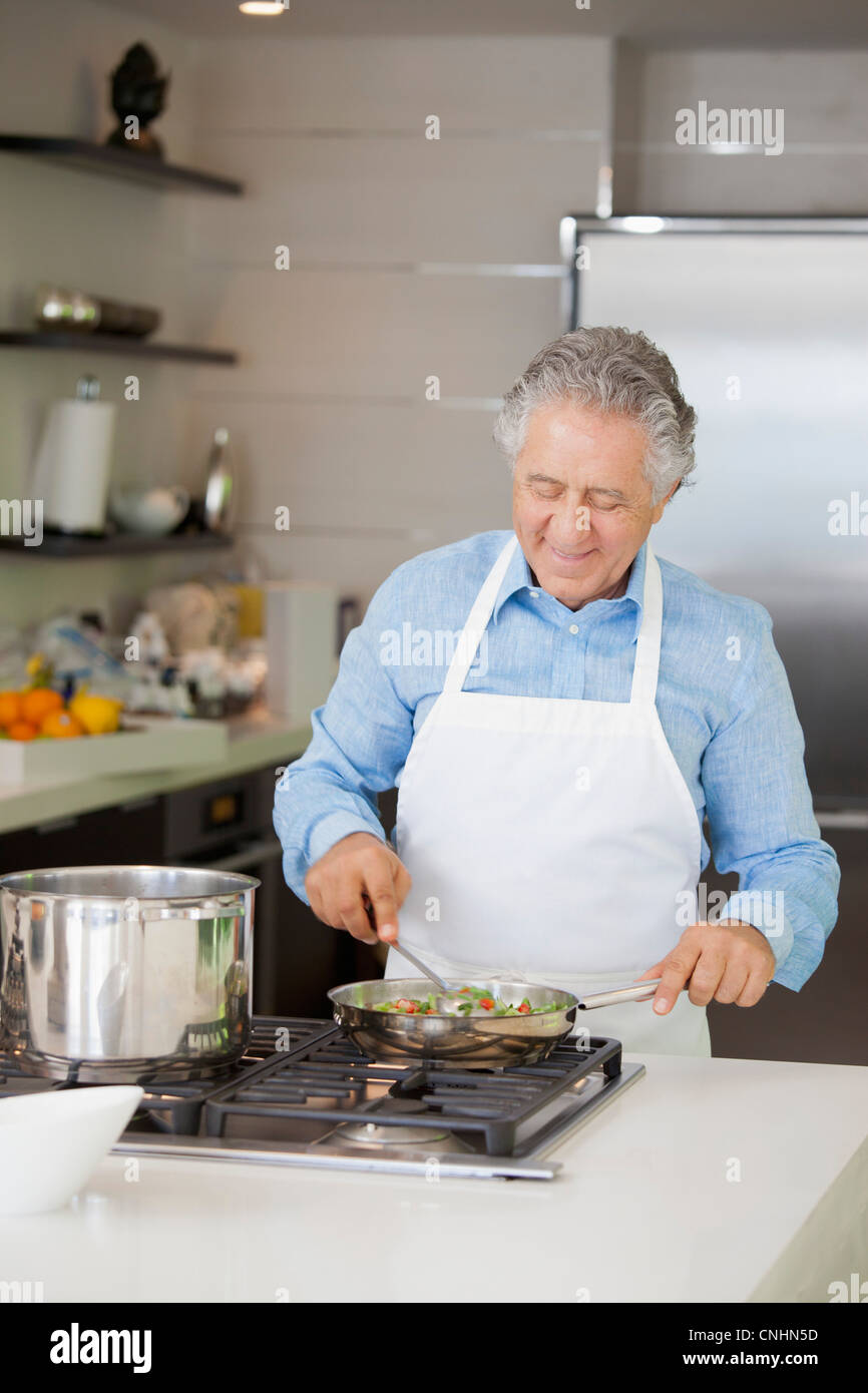 A senior man cooking vegetables in a saute pan Stock Photo