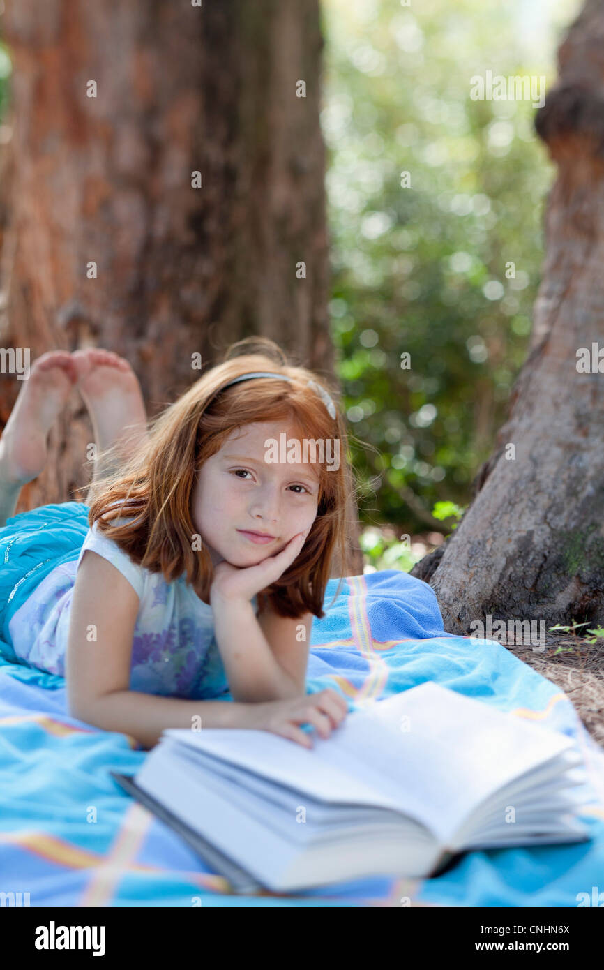 Girl lying on blanket in park with book Stock Photo Alamy