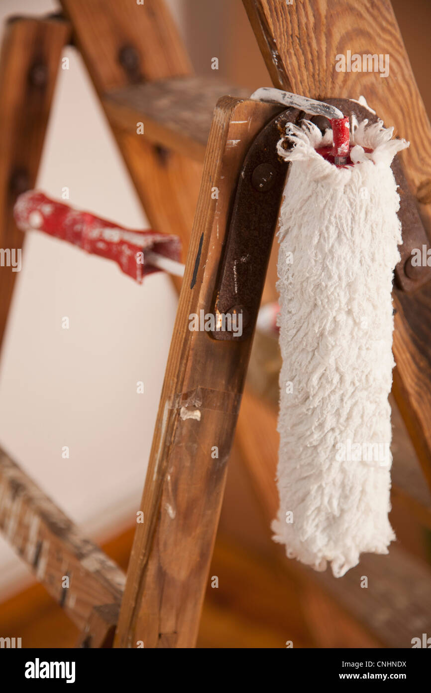 A paint roller hanging from a wood step ladder, close-up Stock Photo