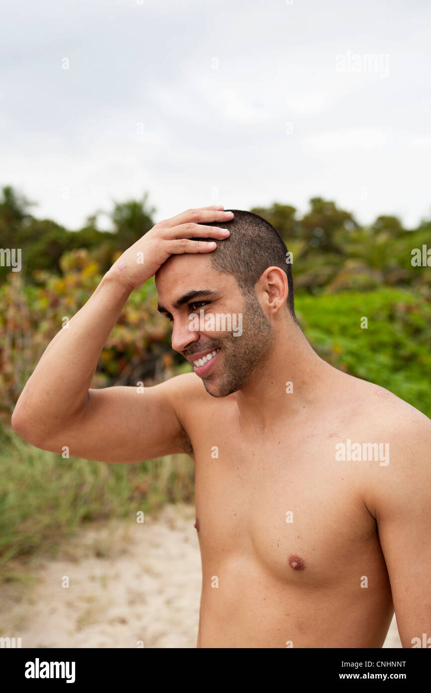 A cheerful young man rubbing his head at the beach Stock Photo Alamy