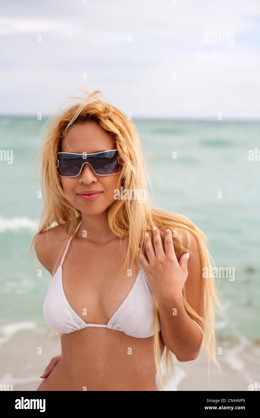 A beautiful young woman in a bikini and sunglasses at the beach Stock Photo